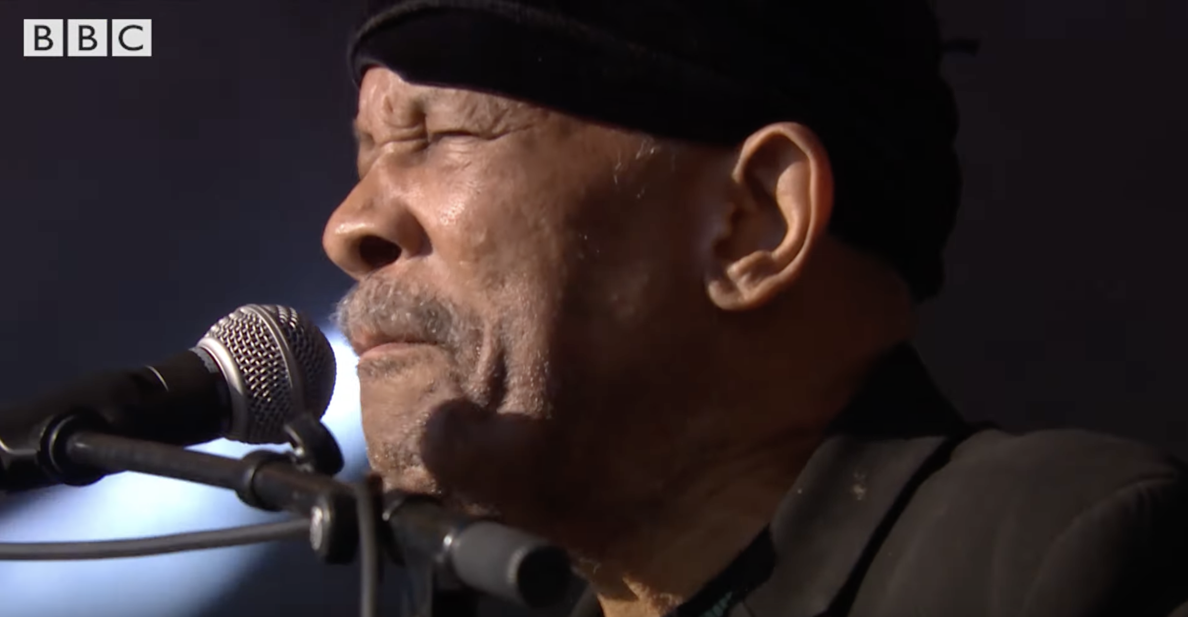 Roy Ayers stands in front of a microphone on the stage at Glastonbury.