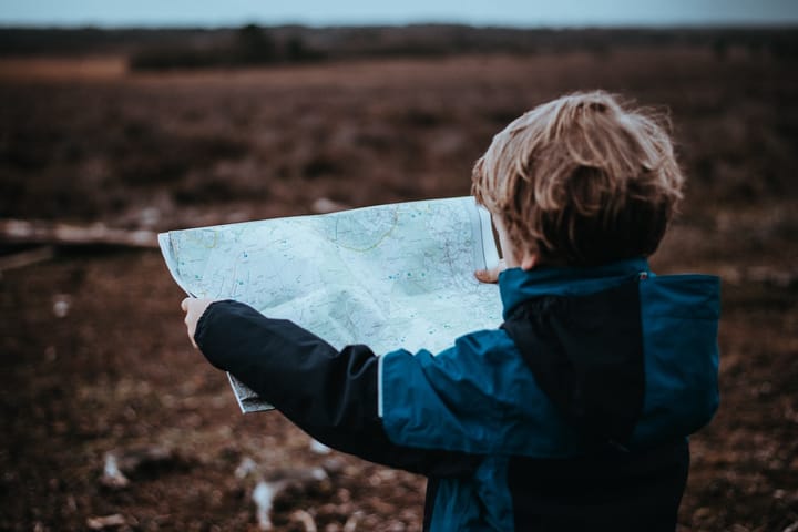 A child holds a map outside. 